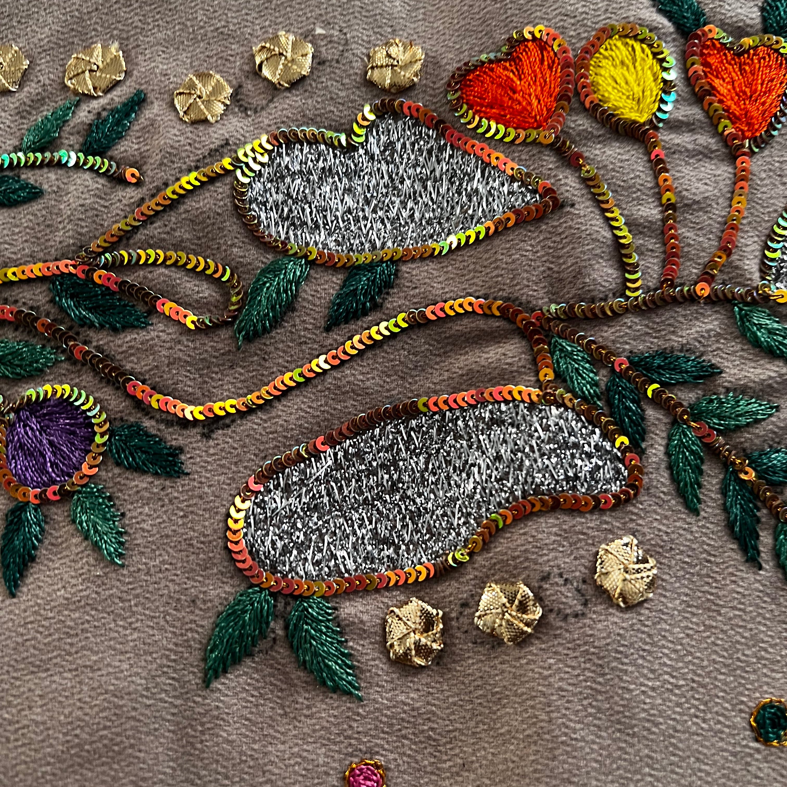Close-up of intricate embroidery with colorful leaves and flowers on a brown background