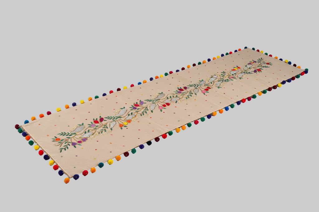 Decorative fabric with embroidery and pom-poms on a dark background