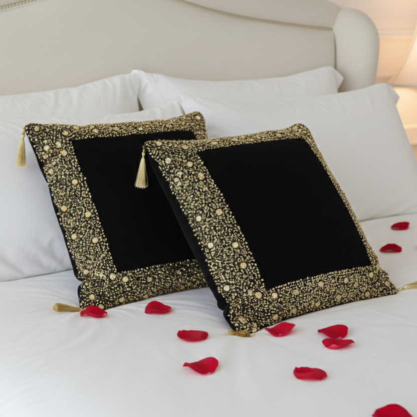 Two decorative pillows with black centers and gold trim on a white couch.